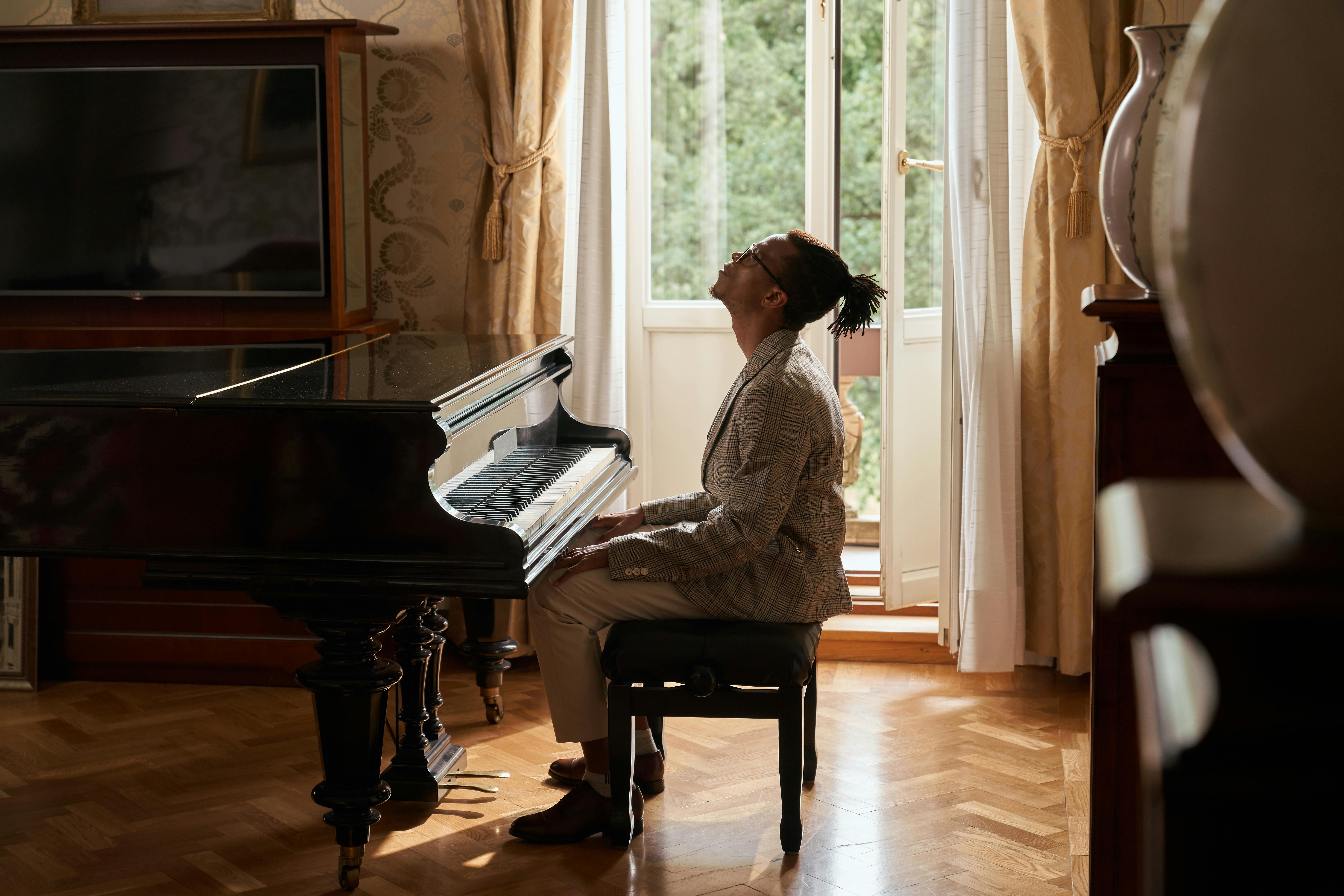 Pianino s hráčem u otevřeného okna v bytě. 